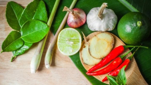 A selection of fresh Thai herbs and spices, including lemongrass, garlic, lime, chili peppers, and other aromatic ingredients, ready to infuse vibrant flavours into Thai cuisine