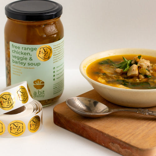 Bowl of soup with a jar of free range chicken, veggie, and butter soup on a white background