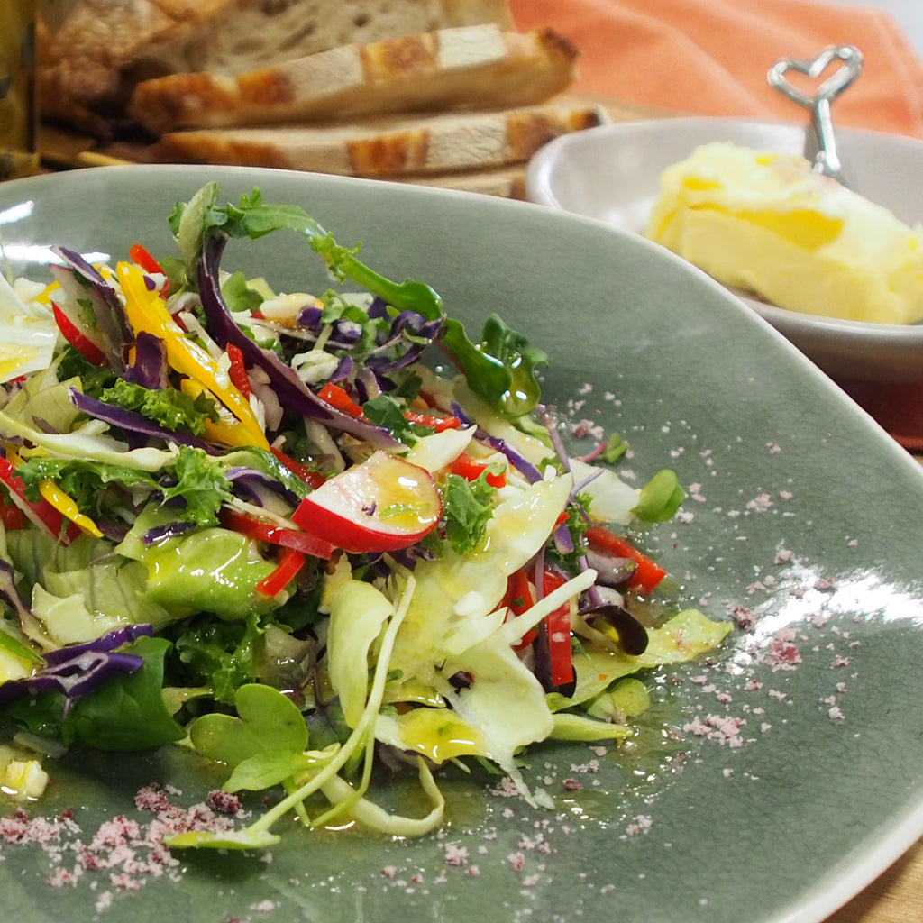 A fresh salad with A Bit Dressy Vinaigrette drizzled on top, adding a burst of flavour and zest to the dish.