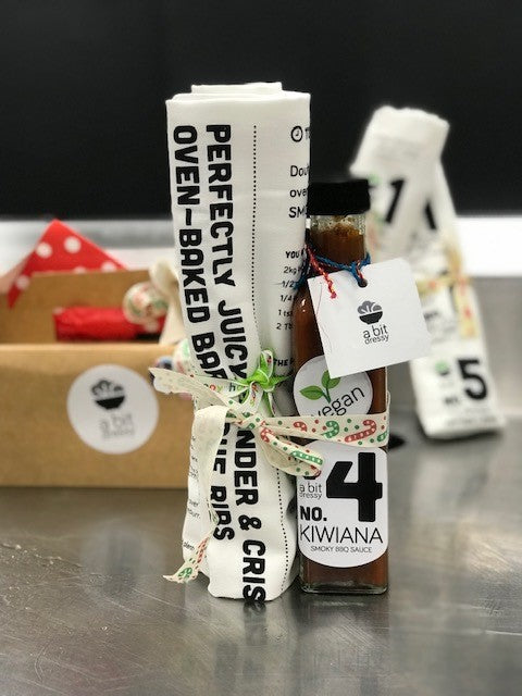 A gift set featuring a bottle of barbecue sauce and a tea towel, offering a delightful combination for enhancing your barbecue experience.