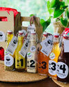 Six distinct dressing bottles, each labeled with their respective names - "Umboshi," "Kiwiana," "Vietnamese," and "Classic Honey," showcasing a variety of flavorful and diverse dressing options