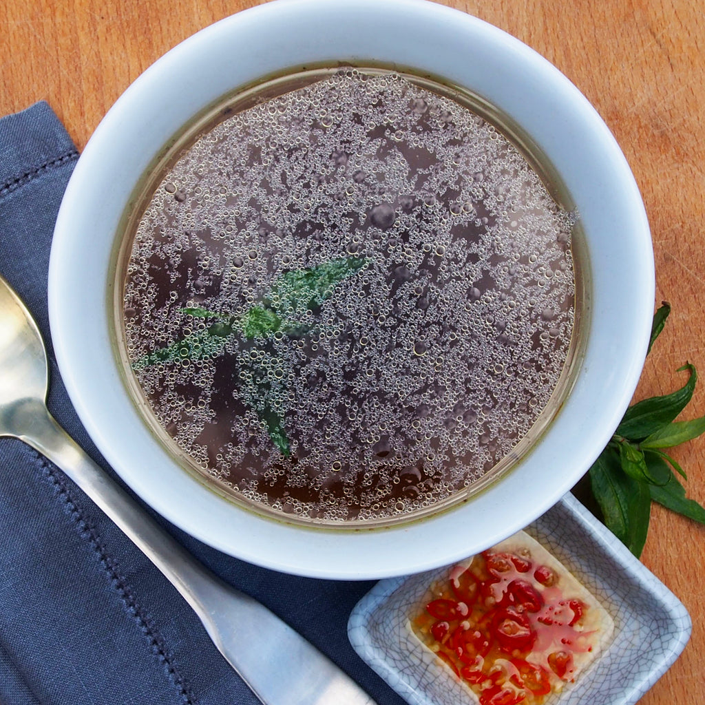 A flavorful beef broth pho bowl carefully crafted with herbs and various condiments, creating a traditional and delicious Vietnamese dish.