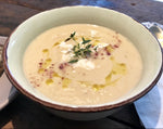 A bowl of roasted cauliflower and garlic soup made with chicken broth, featuring a creamy and flavorful blend of roasted cauliflower and aromatic garlic. Garnished with Balinese salt and Truffle Oil.