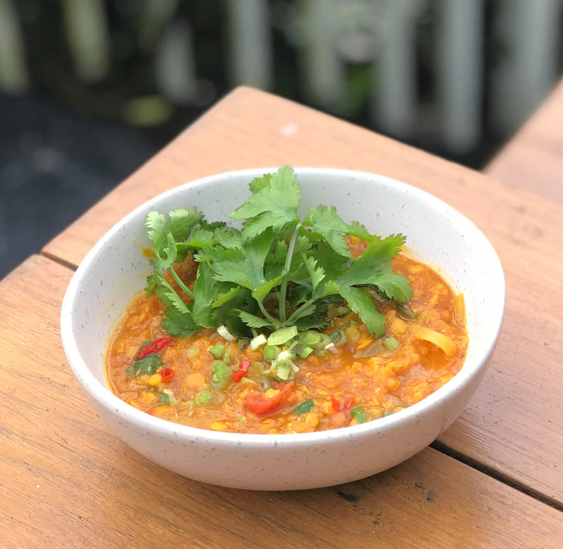 A bowl of Lara's Divine Vegetarian Dahl, a flavorful and aromatic dish with a rich blend of lentils and spices, garnished with coriander, showcasing a delicious and comforting meal.