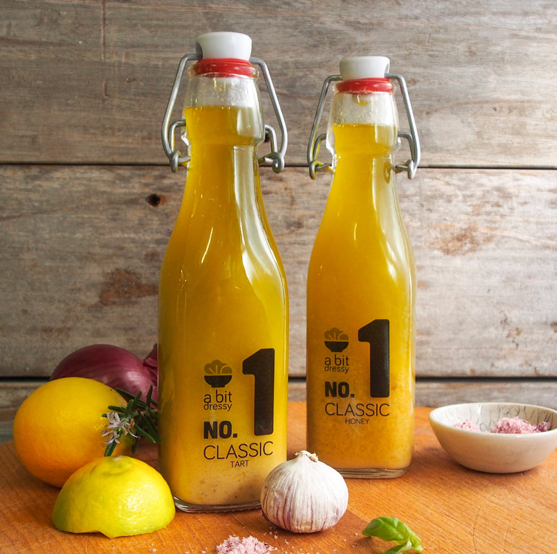 A bottle of No.1 Classic Tart and No.1 Classic Honey positioned alongside an assortment of fresh herbs and flavors, creating an inviting and flavorful culinary display.