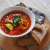 A bowl of taco soup presented next to a few slices of bread, offering a tasty and comforting meal.