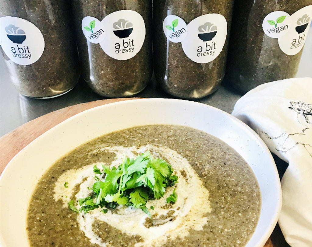 A bowl of Gourmet Roasted Mushroom Soup with thyme and garlic, beautifully presented, with additional jars of the soup displayed in the background