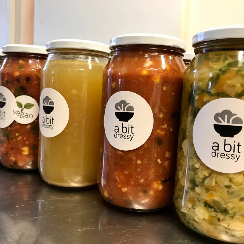 An assortment of healthy soups and broths, each displayed in glass jars, featuring a range of vibrant colors, textures, and ingredients, providing a diverse and nutritious selection