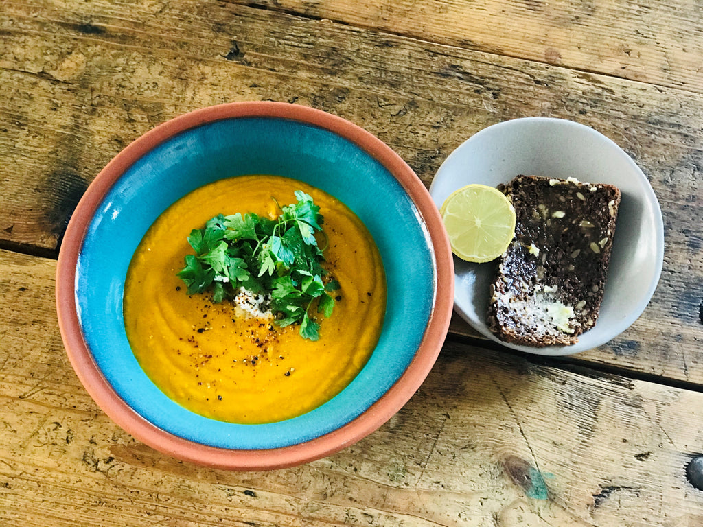 A bowl of Thai Pumpkin Soup with coriander, lemongrass, and chili, presented as a vegan dish with vibrant and aromatic flavors.