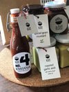 A bottle of Kiwiana BBQ Sauce positioned next to a jar of Spiced Grain Mustard and Roasted Garlic Aioli, offering a delightful selection of condiments for enhancing your dishes.