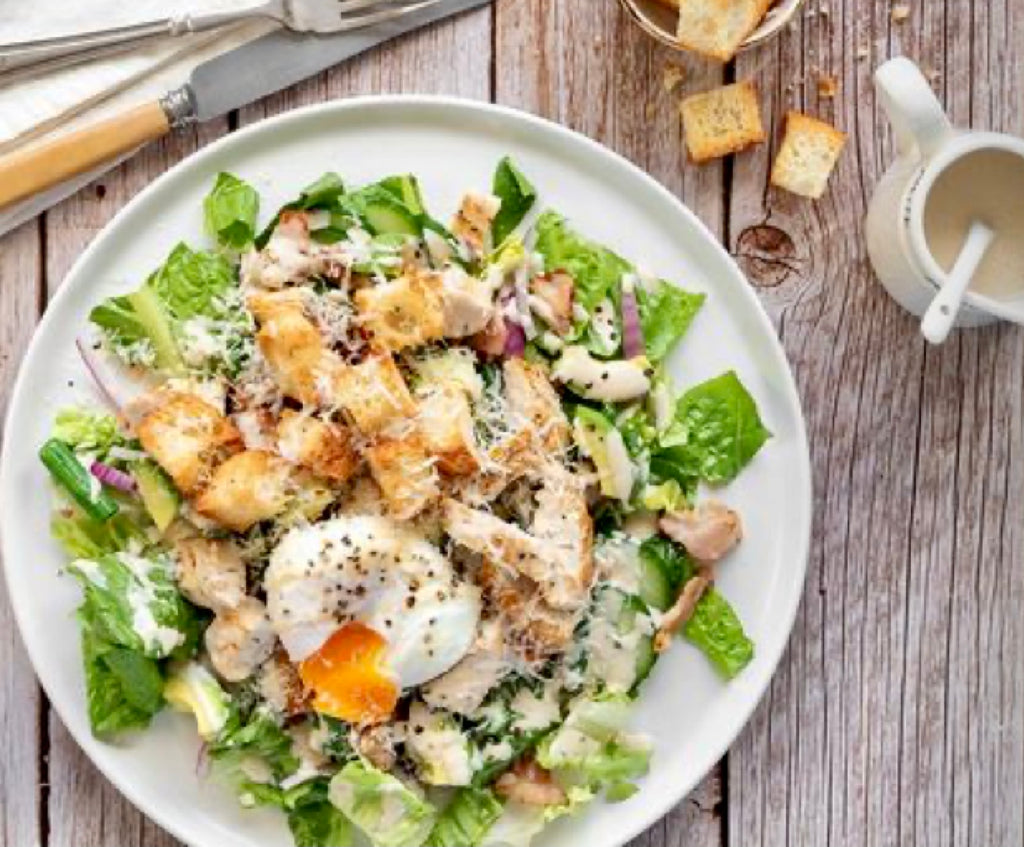 A vibrant and delicious Caesar salad, featuring crisp romaine lettuce, seasoned croutons, grated Parmesan cheese, and creamy Caesar dressing, garnished with fresh black pepper.
