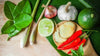 A selection of fresh Thai herbs and spices, including lemongrass, garlic, lime, chili peppers, and other aromatic ingredients, ready to infuse vibrant flavours into Thai cuisine