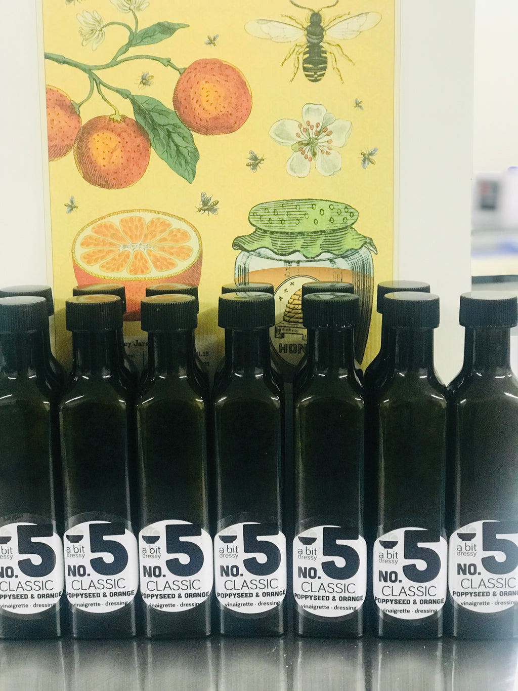Several bottles of Lara's Number 5 Classic Vegan Poppyseed and Orange Vinaigrette, a delightful and zesty dressing perfect for enhancing your salads and dishes.