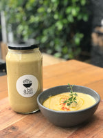 A glass jar of roasted cauliflower and garlic soup with chicken broth placed beside a bowl of the same soup, ready to enjoy the rich and creamy flavors.