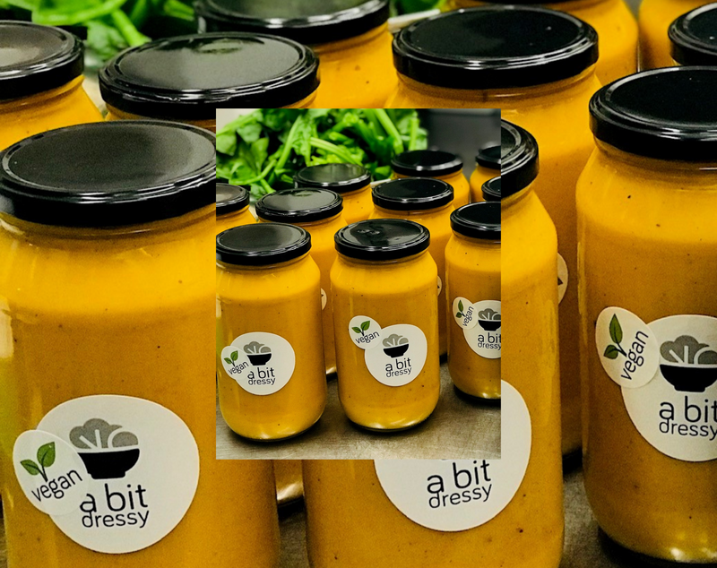 Glass jars filled with vegan Kumara, Carrot & Cardamom Soup infused with ginger and orange, displaying a vibrant, velvety soup with a medley of flavours.