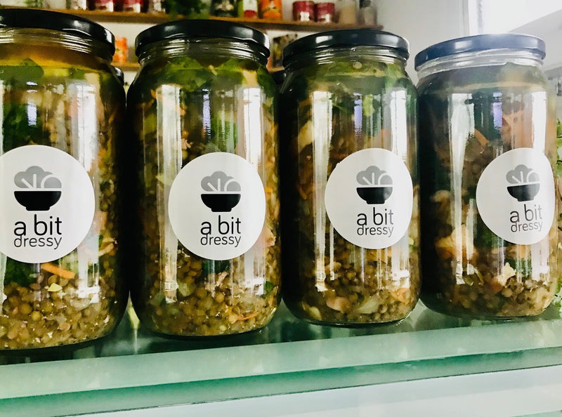 Several glass jars filled with vegan lentil soup, displaying a hearty, rustic blend of lentils and vegetables, ready to enjoy.