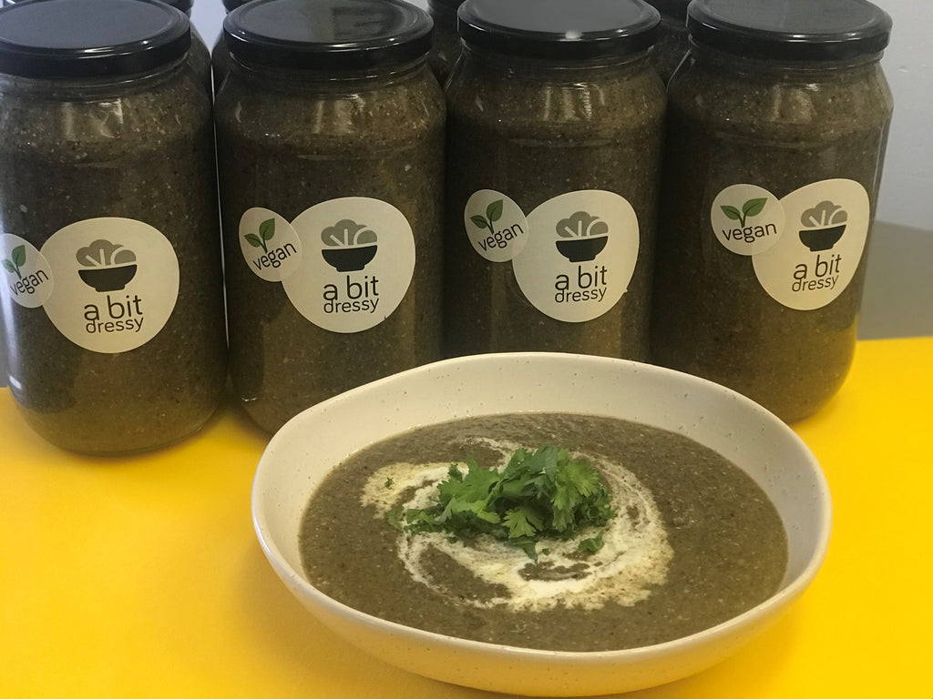 A bowl of Gourmet Roasted Mushroom Soup with thyme and garlic, presented with aromatic herbs on top, with glass jars filled with the same soup in the background