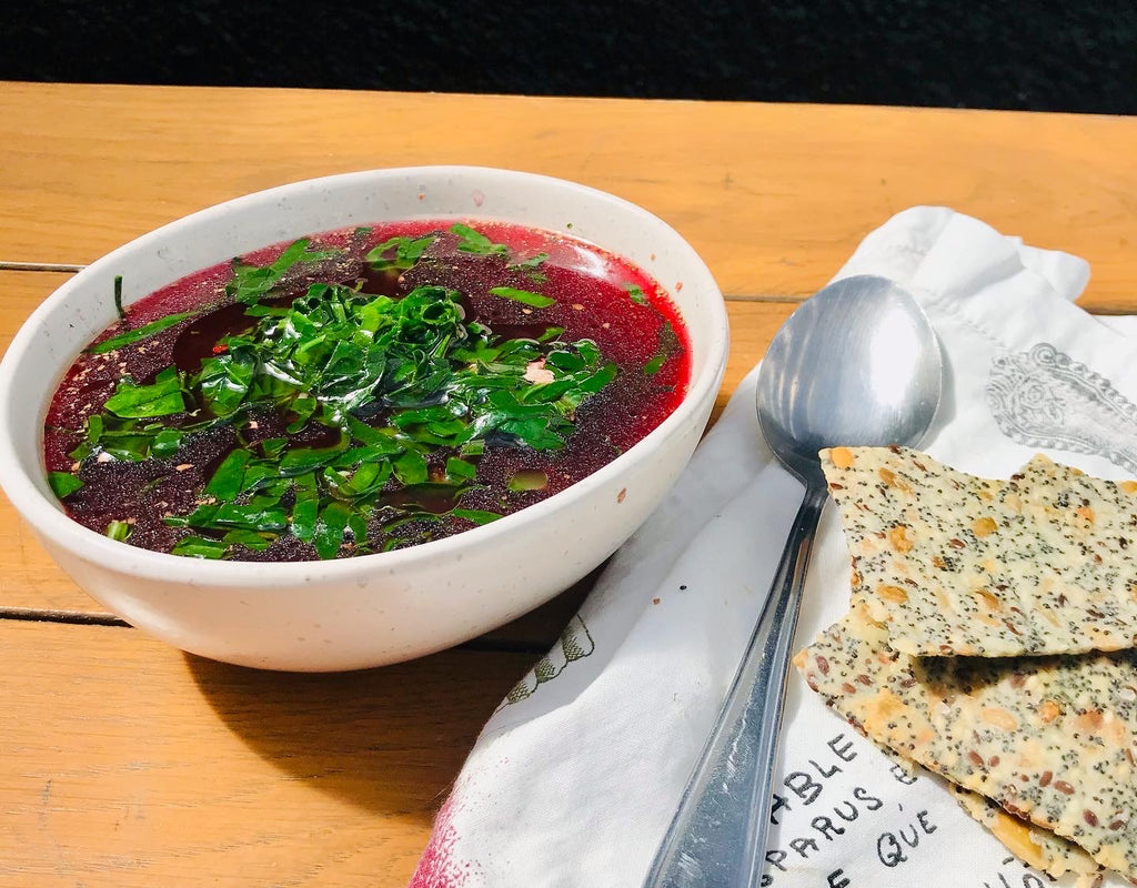 A Wellness Detox Bowl Broth next to a couple of crackers, presenting a nourishing and wholesome meal with a side of crackers.